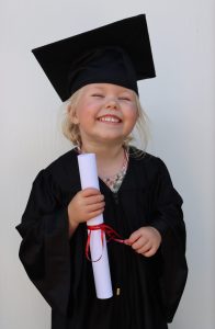 child holding diploma and smiling